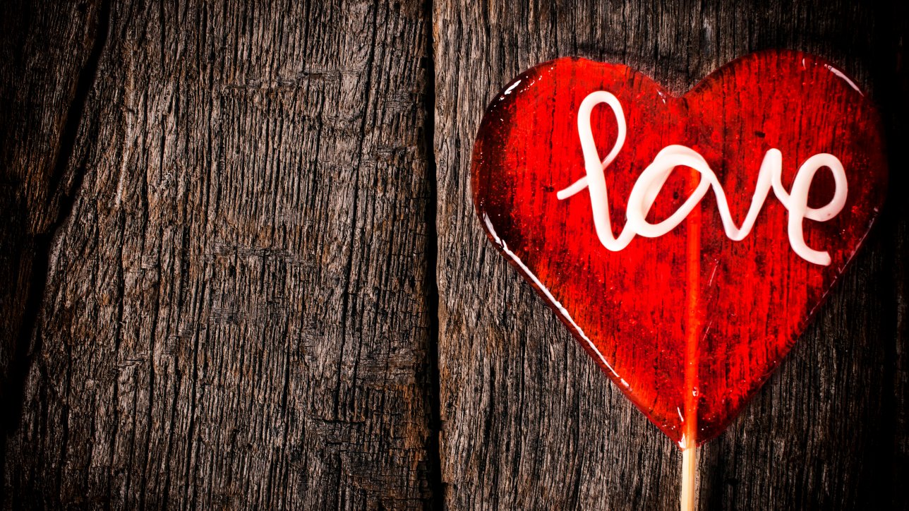 Heart shape lolly pop on the wooden background with empty space