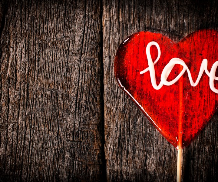 Heart shape lolly pop on the wooden background with empty space